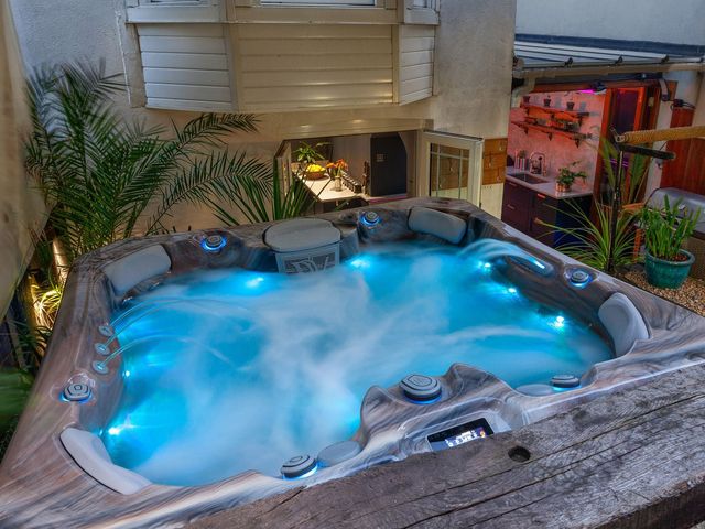 A hot tub with blue lighting in an outdoor courtyard with plants and an open kitchen area at Zanzibar Beach House in St Leonards-On-Sea