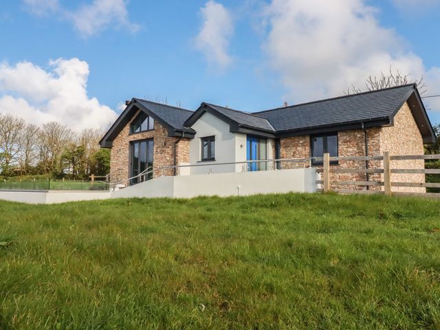 A house with a lawn and fence at Lake View Kestle Mill near Quintrell Downs