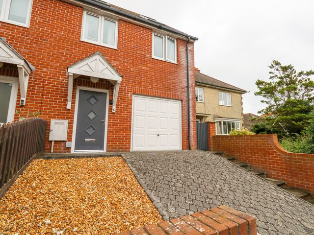 A brick house with a grey door garage and driveway at Dotties Retreat in Weymouth