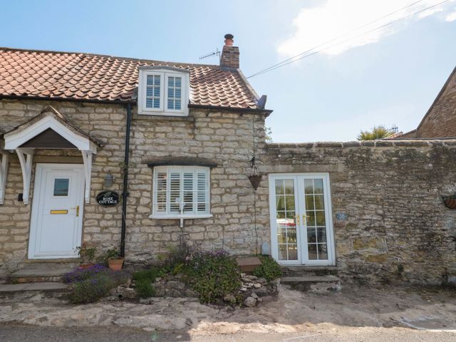 A cottage exterior with a door and windows at Rose Cottage East Ayton