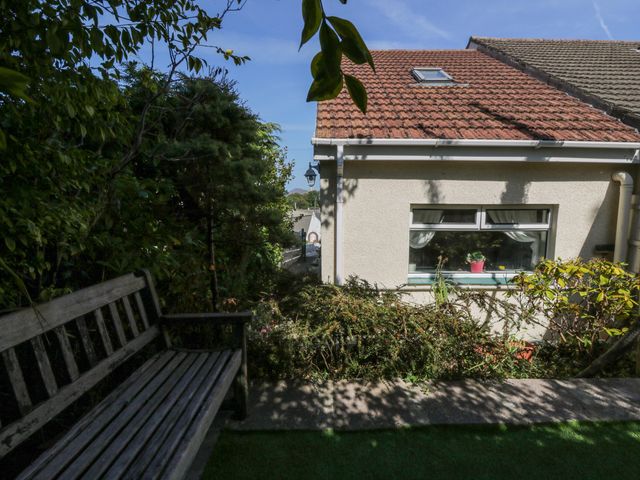 A garden view with a bench and a house at Harbour High Annex Fishguard