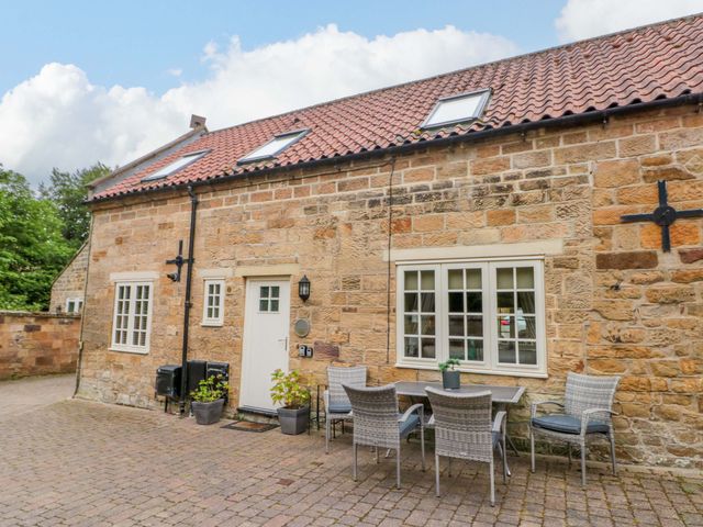 An outdoor seating area with a table and chairs at Clematis Cottage in Whitby