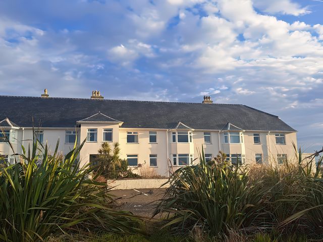 A building with windows and a roof surrounded by plants at Plas Darien Apartment 7 Trearddur Bay