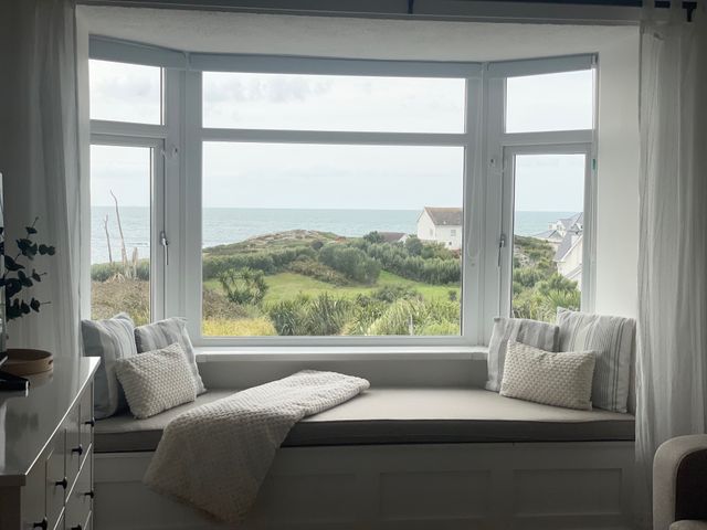 A seating area by a window overlooking the sea at No.7 Plas Darien Trearddur Bay
