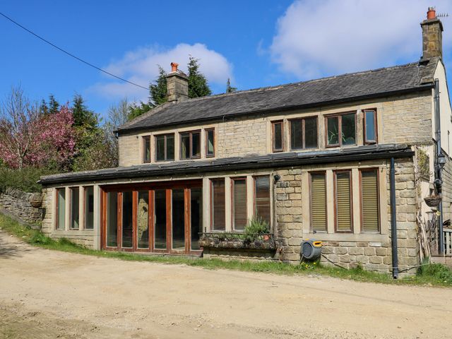 A stone house with multiple windows and a dirt road in front at Pule Hill Farm in Marsden