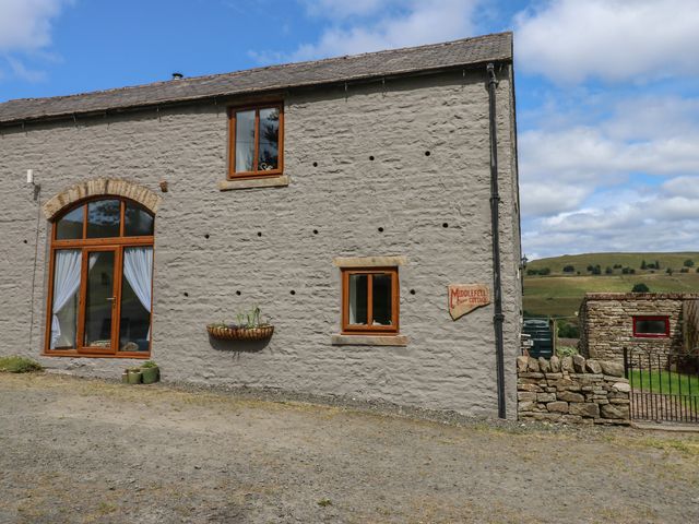 A cottage exterior with windows and gravel space at Middlefell View Cottage in Alston