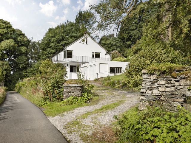 A house surrounded by trees and a gravel driveway at Tethers End in Lindeth near Bowness-On-Windermere