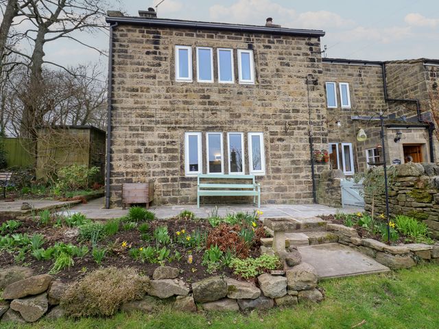 An outdoor area with a house, bench, and garden at Barley Cote Farm in Riddlesden