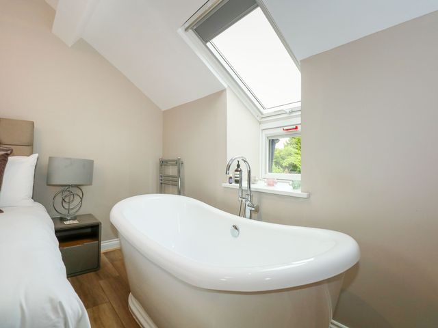 A bedroom with a white bathtub next to a bed and a window at Daisys Place in South Creake near Little Walsingham