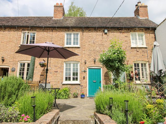 A cottage facade with a garden and umbrella at Medlar Cottage Ironbridge