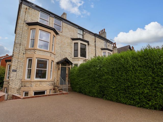An exterior view of a house with a hedge and driveway at The Corner House Scarborough