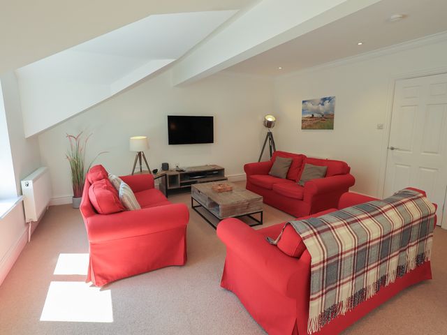 A living room with red sofas and a coffee table at Waterfall in Ambleside