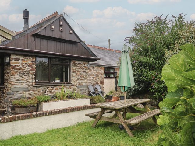 A garden with a picnic table and an umbrella at The Old Stable near Holywell Bay