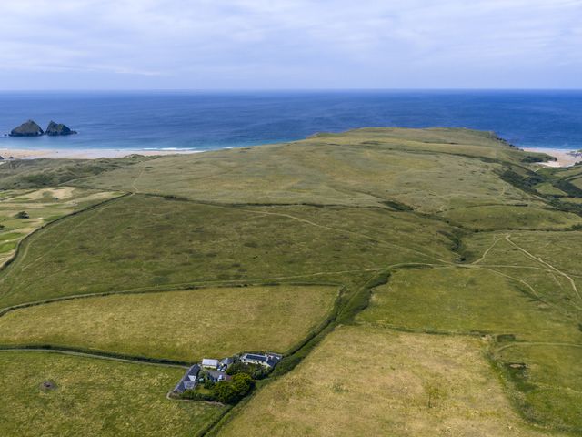 An aerial view of a house near the ocean and hills at The Old Stable near Holywell Bay