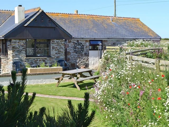 A building with a garden and picnic table at The Old Stable near Holywell Bay