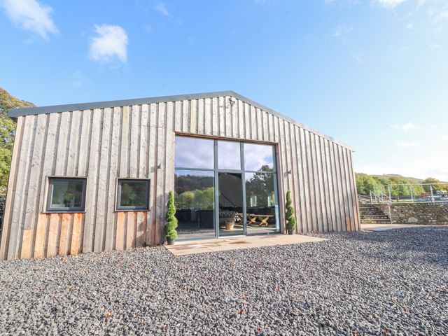 A wooden building with large glass doors and two small windows surrounded by gravel at The Old Sheep House in Langcliffe near Settle