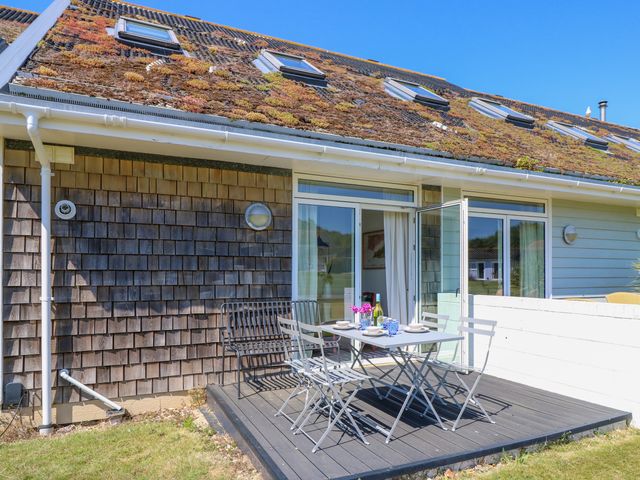 An outdoor patio with table and chairs outside a house with a green roof at J21 Vermont near Yarmouth