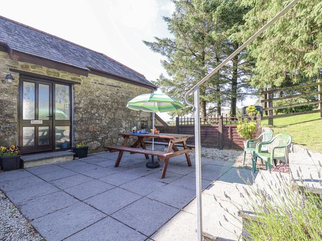 An outdoor seating area with a picnic table and umbrella at The Hayloft in Common Moor near Liskeard