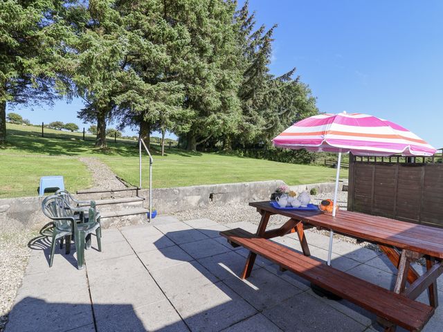A garden with a table and chairs under an umbrella at The Dairy in Common Moor near Liskeard