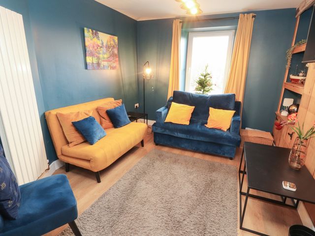A living room with yellow and blue sofas and a coffee table at 10 Keekle Terrace in Keekle near Cleator Moor