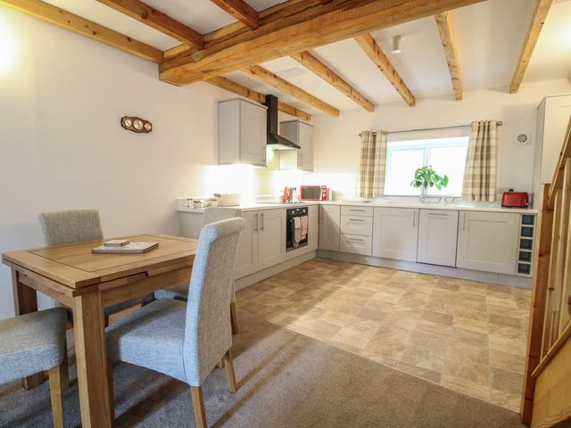 A kitchen with wooden dining table and four upholstered chairs wooden ceiling beams and light gray cabinets at Ascot in Knolton near Ellesmere