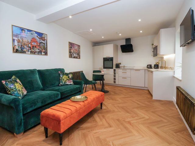 A living room with a sofa and kitchen area at The Old Bakehouse in 