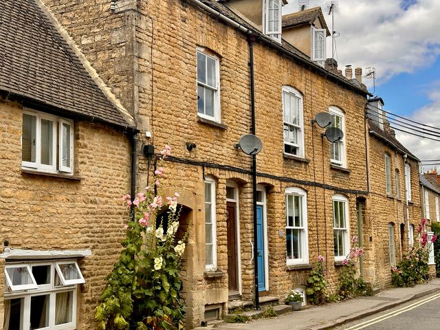 A row of stone buildings with windows and doors at Lamorna Cottage in Chipping Norton