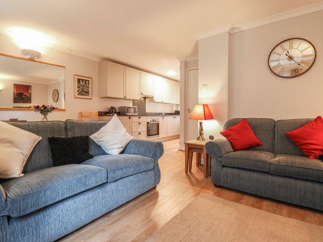 A living room with two sofas with cushions a side table lamp and a kitchen in the background at New Tower House- 10 Pear Tree Court in York