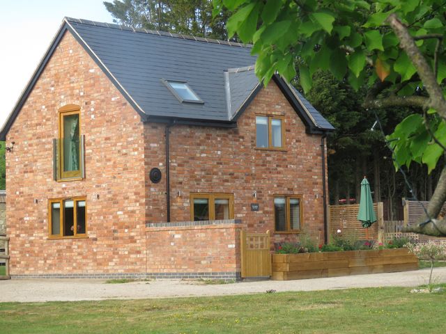 A brick house with windows and a garden at The Cartshed in Defford