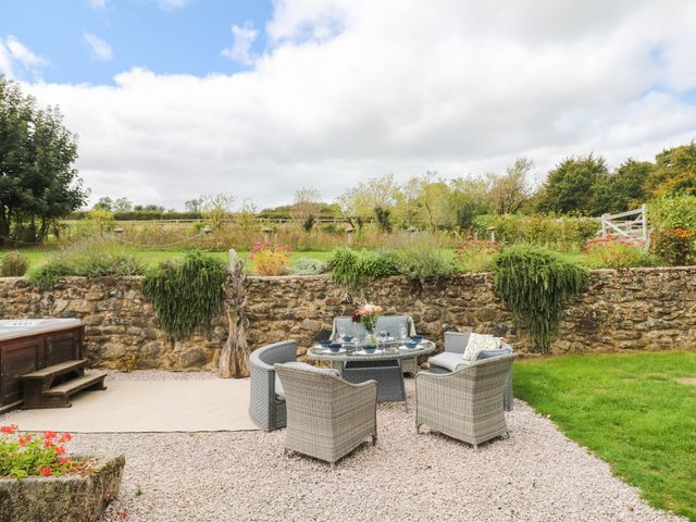 A garden with a table and chairs beside a hot tub at Halshanger Barn Newton Abbot