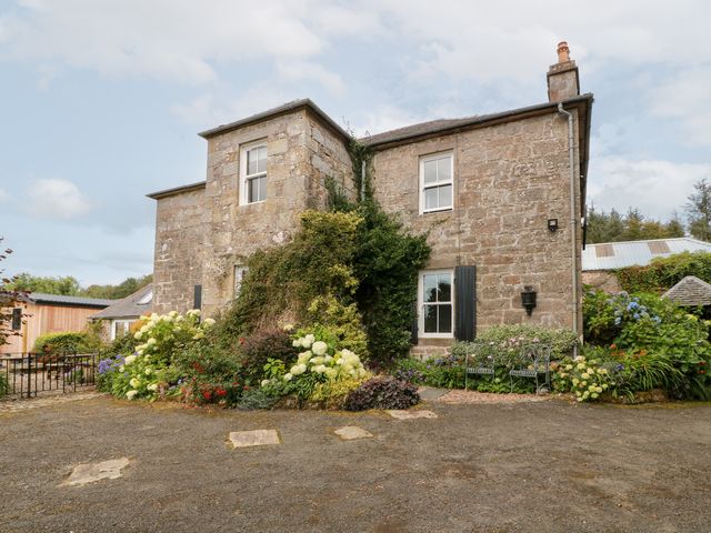 A house with a stone wall and garden flowers at Balsaggart Farm