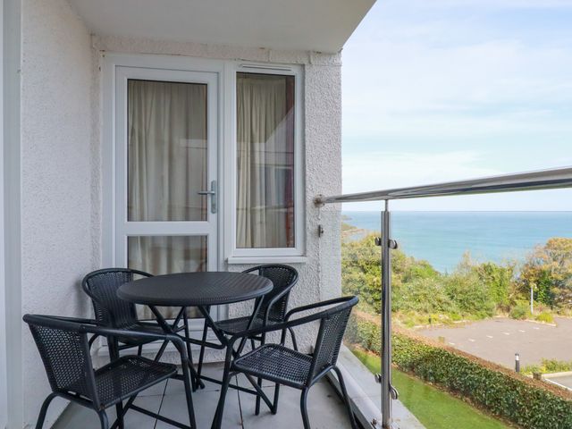 A balcony with a round table and four chairs overlooking the sea at Godrevy View in Carbis Bay