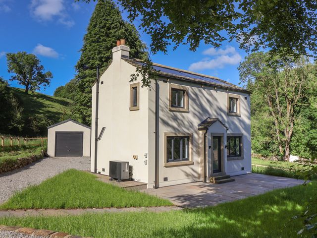 A house with a garage and lawn at Wood Cottage in Skipton