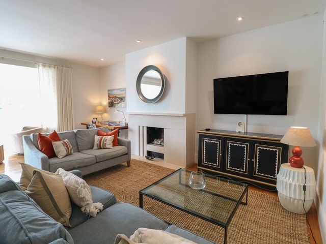 A living room with a sofa, armchair, coffee table, and television at 22 Dart Marina in Dartmouth