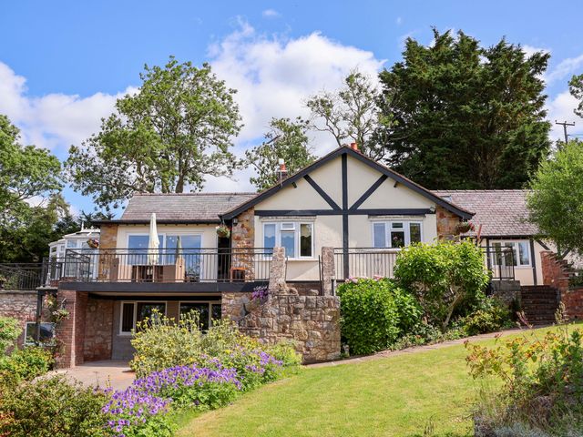 A house with a balcony and garden at The Old Barn in Pentre Celyn