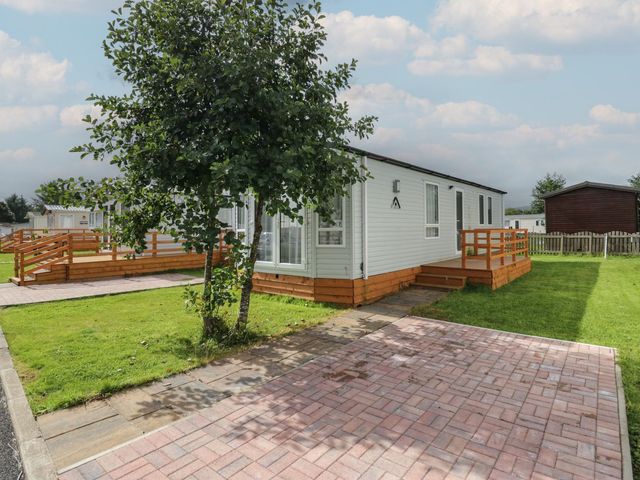 A mobile home with a deck and pathway at Ash in Denny