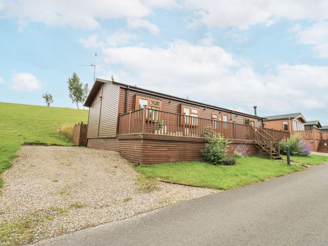 A lodge with decking and gravel driveway at Butterfly Lodge Tunstall near Catterick, North Yorkshire