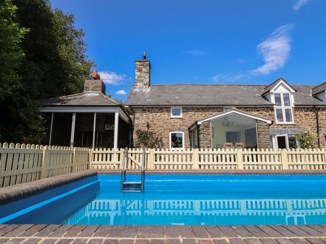An outdoor swimming pool with a house and a fence at Bryn Y Garreg Cottage - The Wireless Free Farm, Llangadfan near Llanwddyn