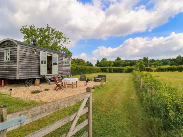An outdoor area with a shepherd's hut and furniture at Goose Whistle Hut in Foxham