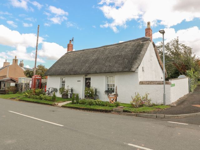 A cottage with a thatched roof and garden at Rowantree Cottage in Kelso