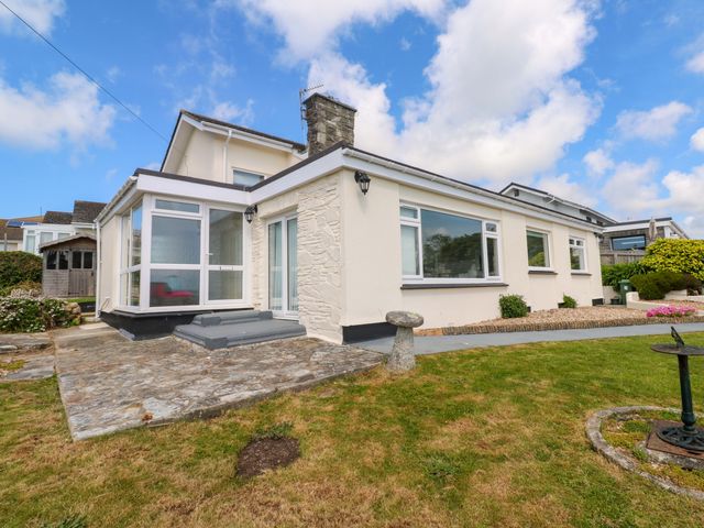 A single story house with stone patio and lawn in the front garden at Karenza in Penzance