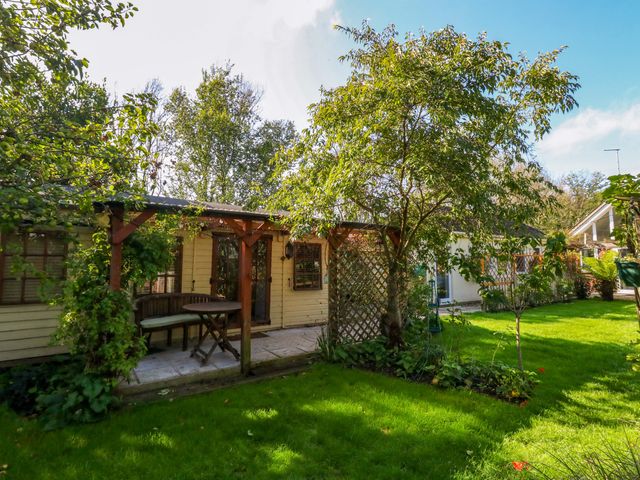 A garden with a shed, table, and trees at The Cabin at Little Timbers Ringwood