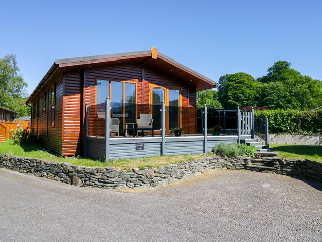 A lodge with a deck and chairs at Dovedale Lodge Troutbeck Bridge