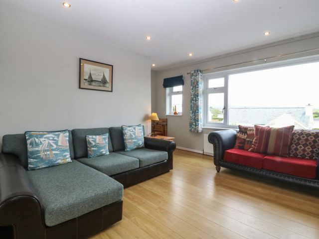 A living room with two sofas and a window showing rooftops at Ty Nant in Abersoch
