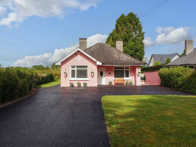 A pink house with a driveway and lawn at Rosemont in Adare