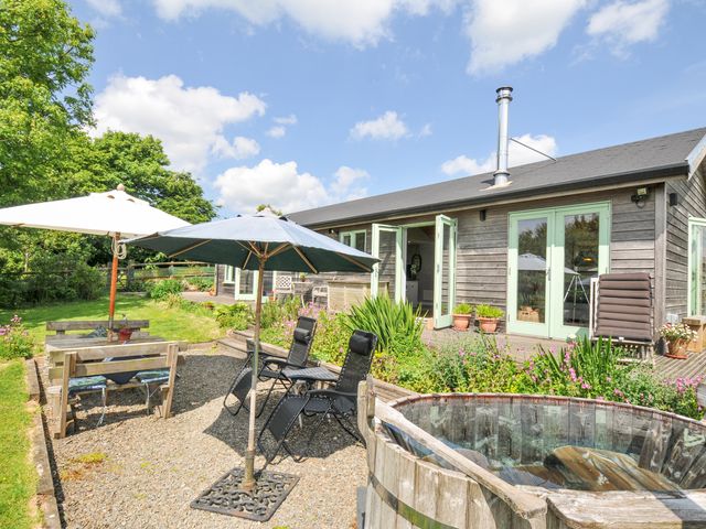 A garden with chairs, table, umbrellas, and hot tub at Smugglers Bodmin Moor, St Breward near St Tudy