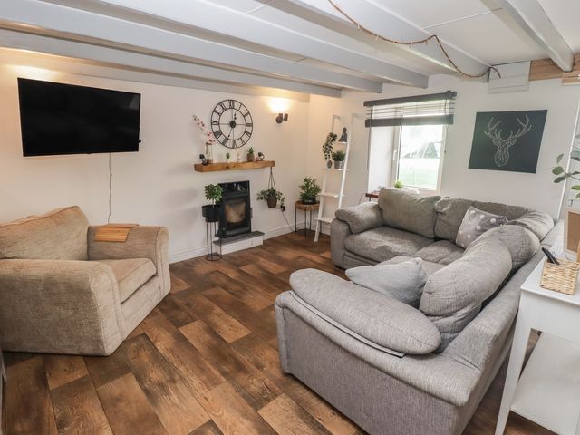 A living room with a television, sofa and armchair at 41 St. James Street Narberth