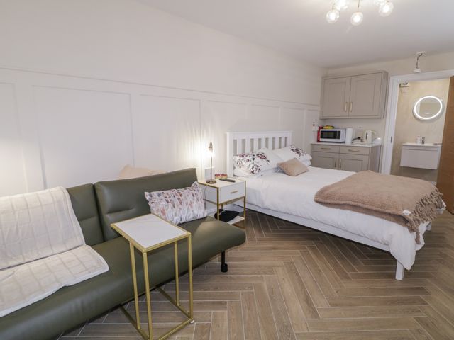 A bedroom with a bed, sofa, and kitchenette at Church Studio in Portstewart
