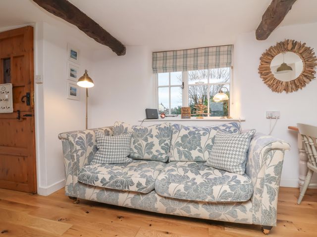 A living room with a patterned sofa a wooden door a standing lamp and a window at Sunnymead in Bickington near Barnstaple