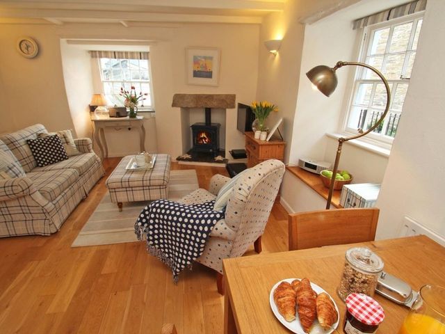 A living room with a fireplace sofa armchair and a wooden dining table at Sunrise Cottage in Padstow